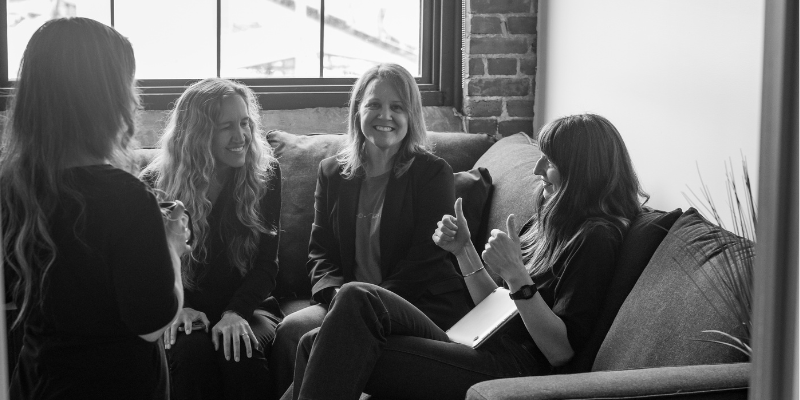 Holly Buttura sits on a couch with colleagues during a collaborative team conversation in Eternity’s office.